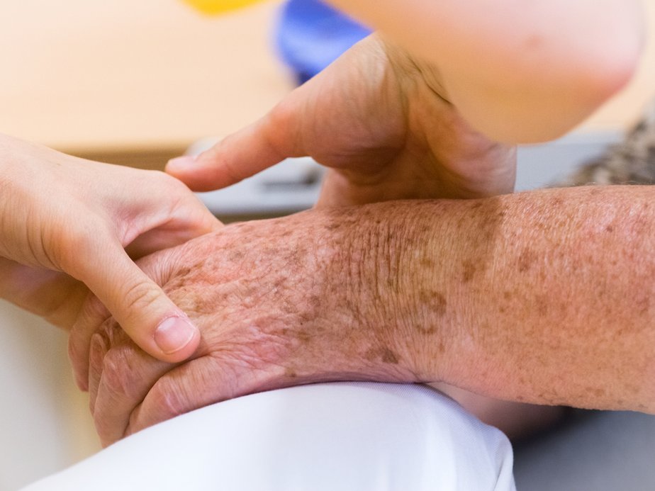 Betreuerin hält Hand einer Bewohnerin.